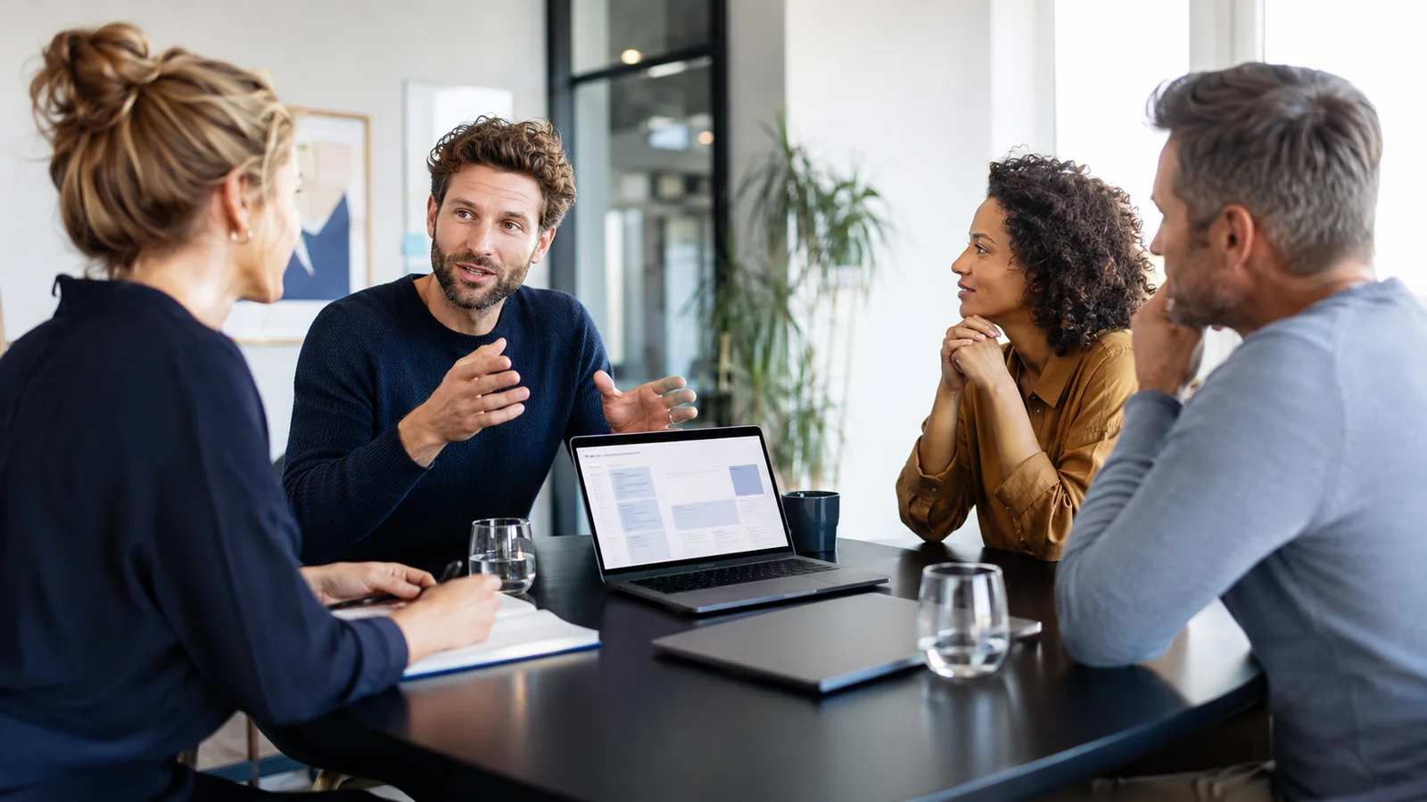 Team im lebendigen Brainstorming mit einem Laptop für digitale Besprechungsnotizen